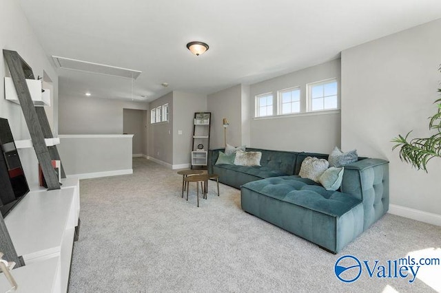 carpeted living room with baseboards and attic access
