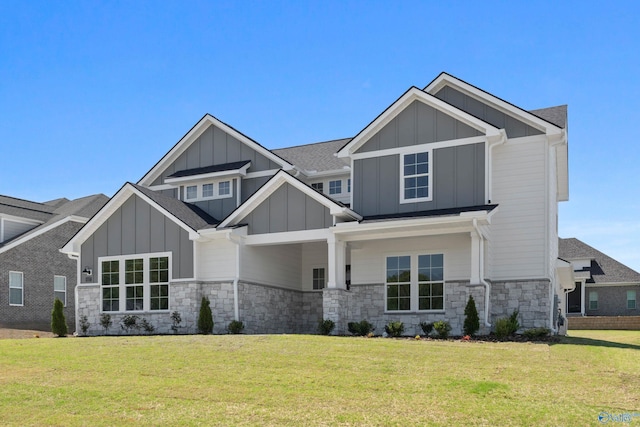 craftsman house with board and batten siding, a front yard, and stone siding