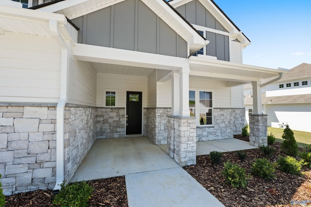 entrance to property with a porch, board and batten siding, and stone siding