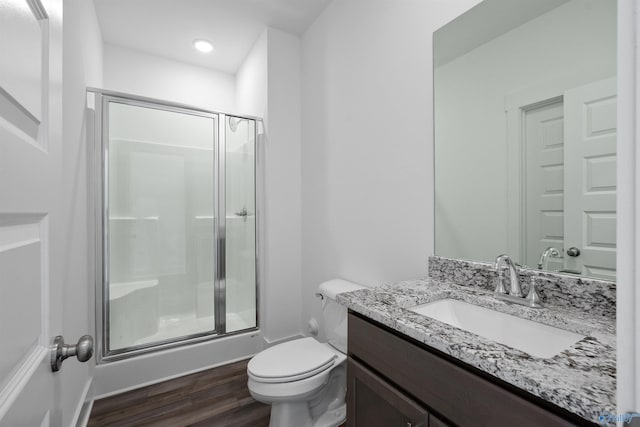 full bath with toilet, a shower stall, wood finished floors, and vanity