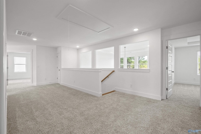 spare room featuring light carpet, attic access, visible vents, and baseboards