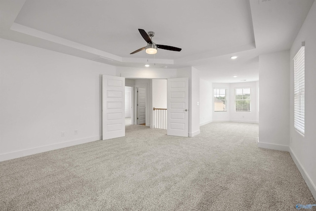 interior space with recessed lighting, a raised ceiling, light colored carpet, and baseboards