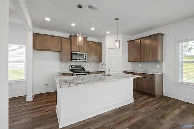 kitchen featuring visible vents, light stone counters, stainless steel appliances, pendant lighting, and a sink