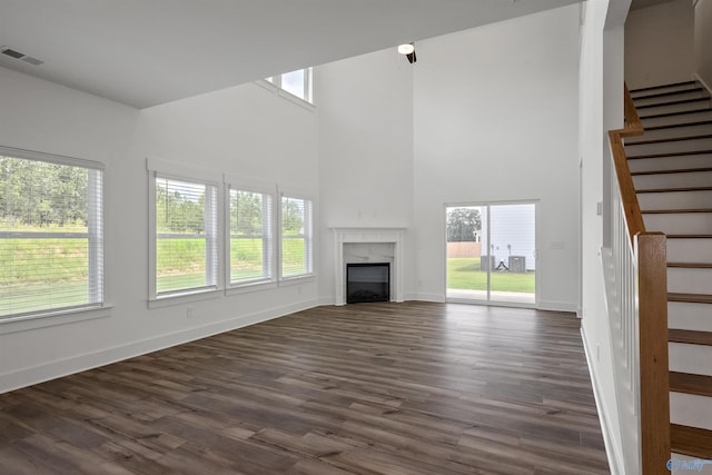 unfurnished living room featuring baseboards, visible vents, dark wood finished floors, stairway, and a high end fireplace