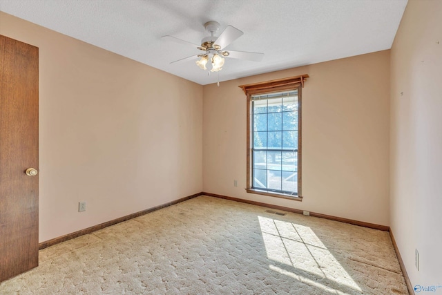 empty room featuring ceiling fan, a textured ceiling, and light carpet