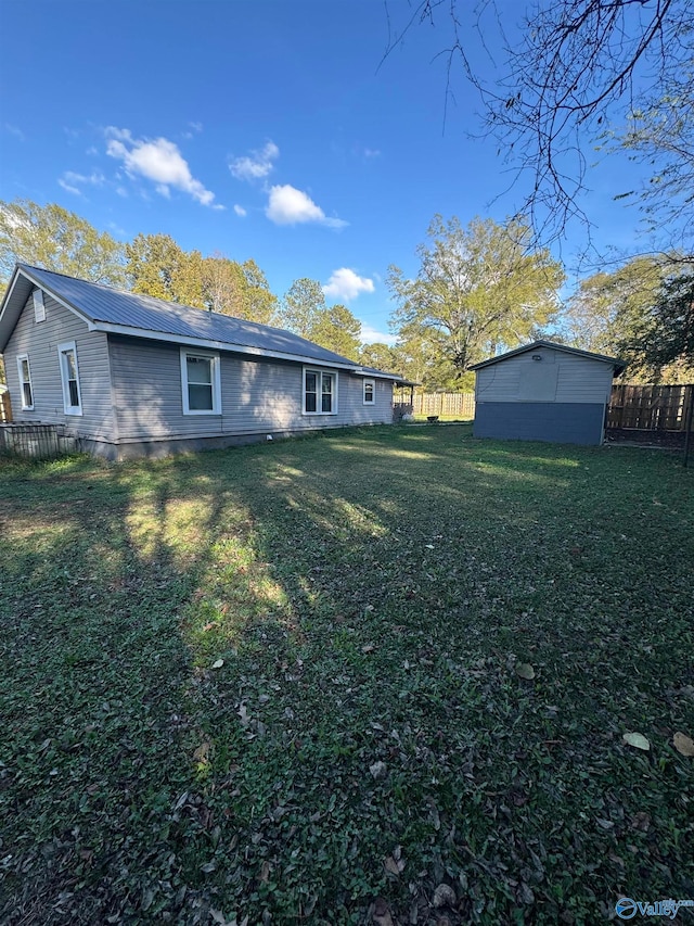 rear view of house featuring a lawn and a storage shed