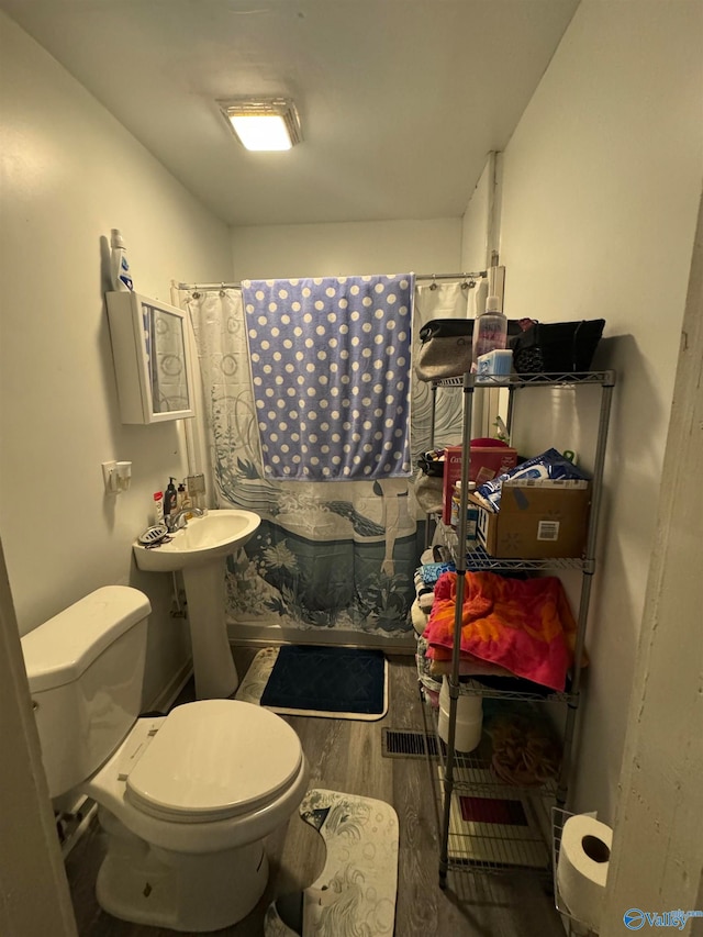 bathroom with hardwood / wood-style flooring, curtained shower, toilet, and sink