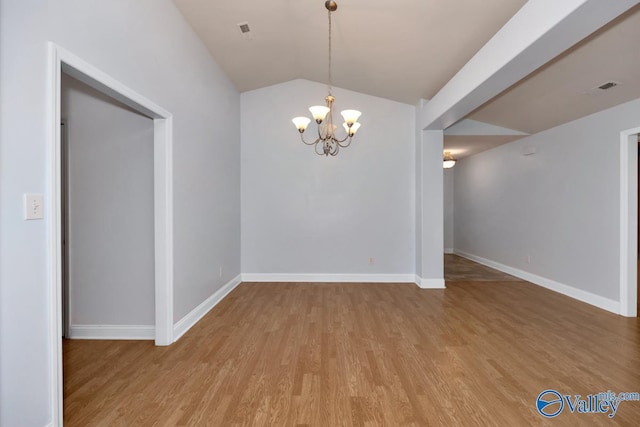 spare room with an inviting chandelier, lofted ceiling, and light wood-type flooring