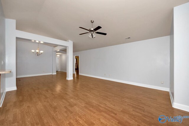 unfurnished living room with hardwood / wood-style floors, ceiling fan with notable chandelier, and vaulted ceiling