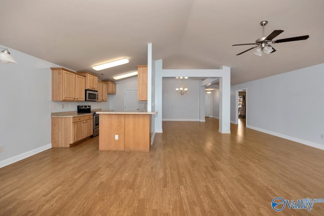 kitchen with stainless steel appliances, light brown cabinetry, vaulted ceiling, and light wood-type flooring