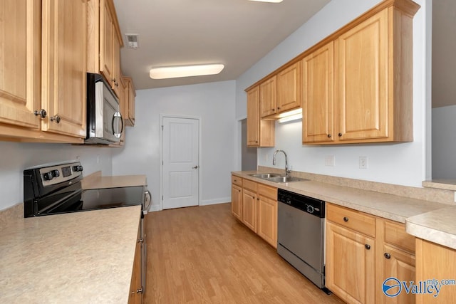 kitchen featuring lofted ceiling, light brown cabinetry, sink, light hardwood / wood-style flooring, and appliances with stainless steel finishes