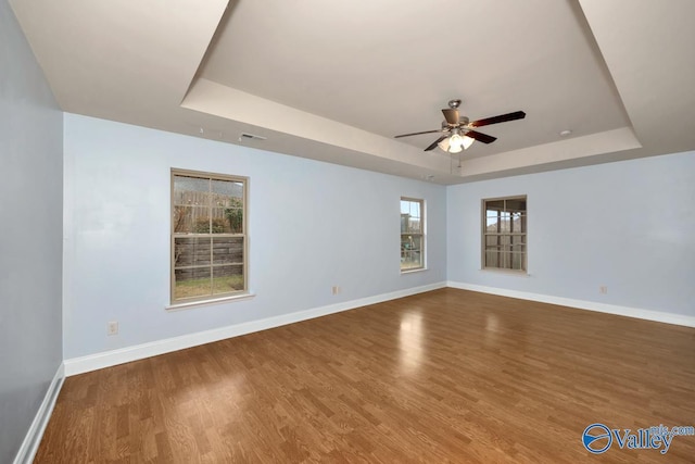 unfurnished room with a raised ceiling, hardwood / wood-style floors, and ceiling fan