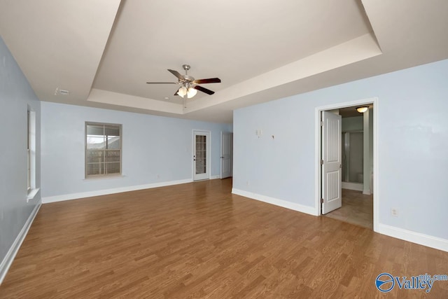 spare room featuring wood-type flooring, ceiling fan, and a tray ceiling