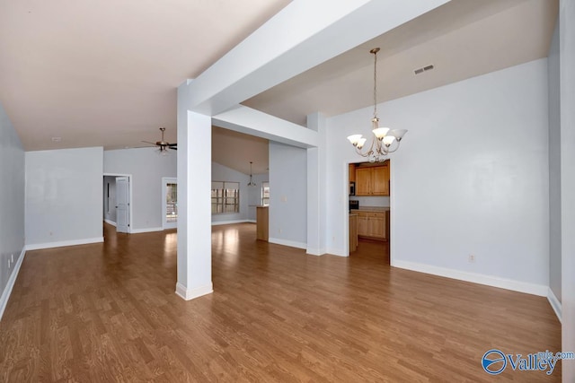 unfurnished living room featuring hardwood / wood-style flooring, lofted ceiling, and ceiling fan with notable chandelier