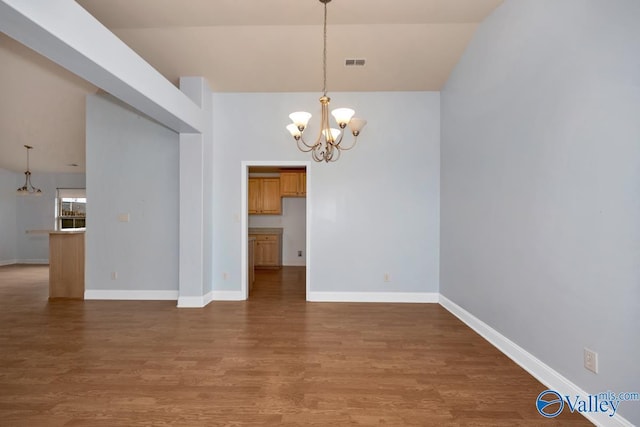 unfurnished dining area with wood-type flooring, lofted ceiling, and a notable chandelier