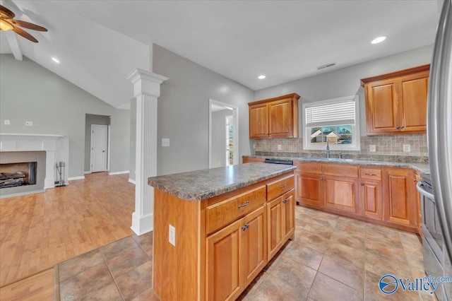 kitchen with a fireplace, a kitchen island, a sink, visible vents, and open floor plan