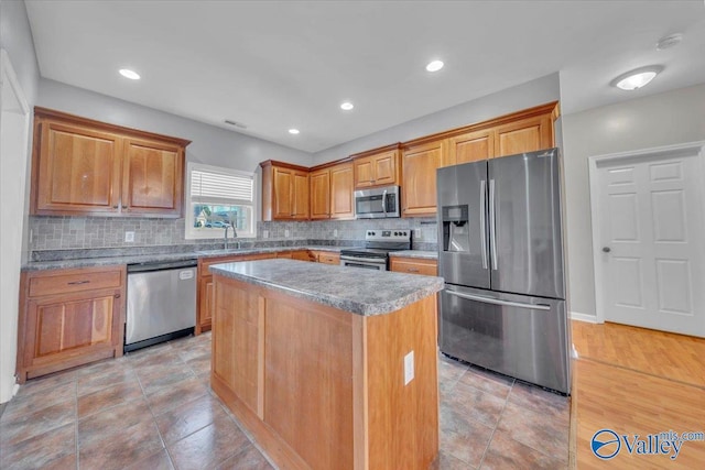 kitchen featuring stainless steel appliances, a sink, decorative backsplash, and a kitchen island