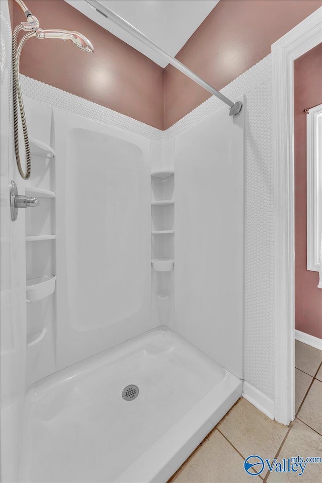 bathroom featuring tile patterned flooring, baseboards, and walk in shower