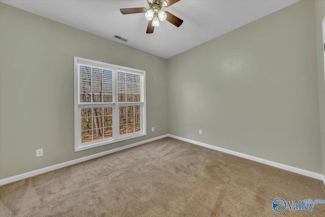 carpeted empty room featuring baseboards, visible vents, and a ceiling fan