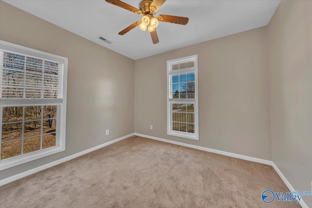 carpeted empty room featuring visible vents, ceiling fan, and baseboards