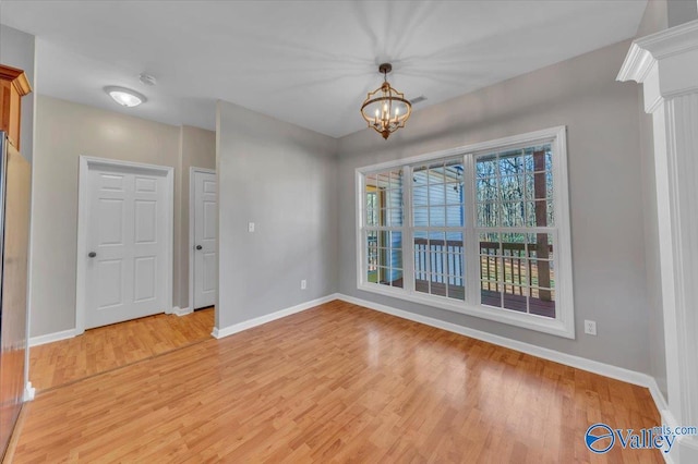 interior space featuring light wood-type flooring, baseboards, and an inviting chandelier