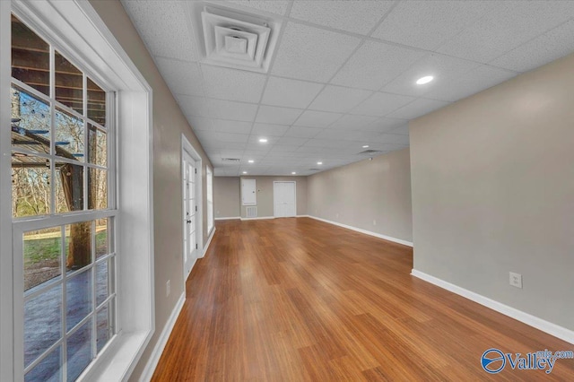 spare room featuring a paneled ceiling, recessed lighting, baseboards, and wood finished floors