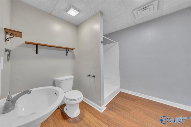 bathroom with visible vents, toilet, wood finished floors, a walk in shower, and a sink