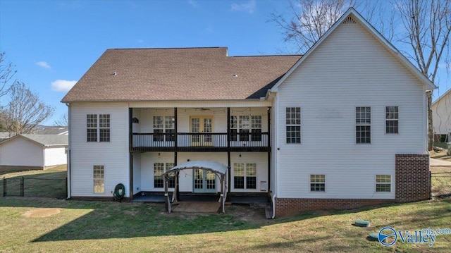 rear view of property with a balcony, roof with shingles, a yard, french doors, and a patio area