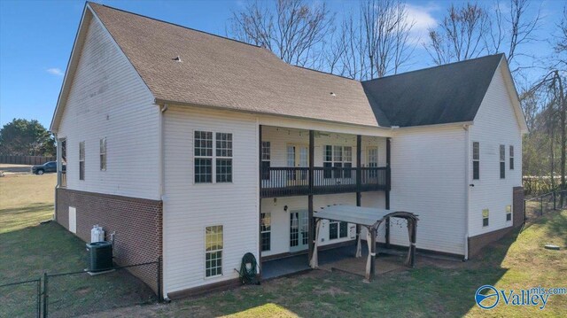 rear view of property with roof with shingles, a lawn, a balcony, and central air condition unit