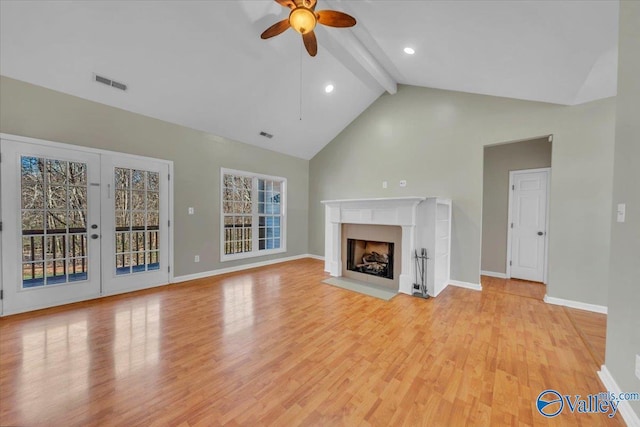 unfurnished living room featuring light wood finished floors, beamed ceiling, a fireplace, and visible vents