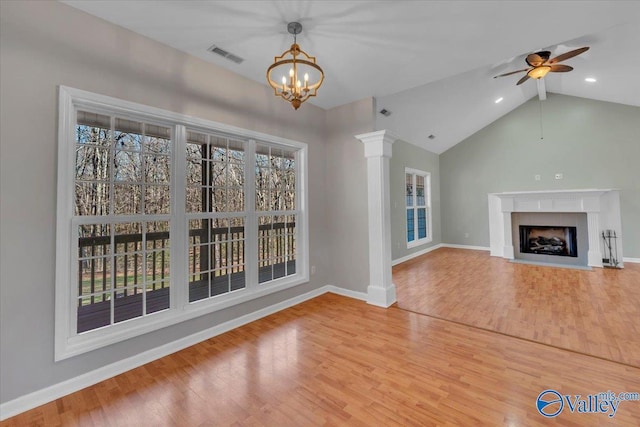 unfurnished living room with visible vents, baseboards, a fireplace with flush hearth, wood finished floors, and ornate columns