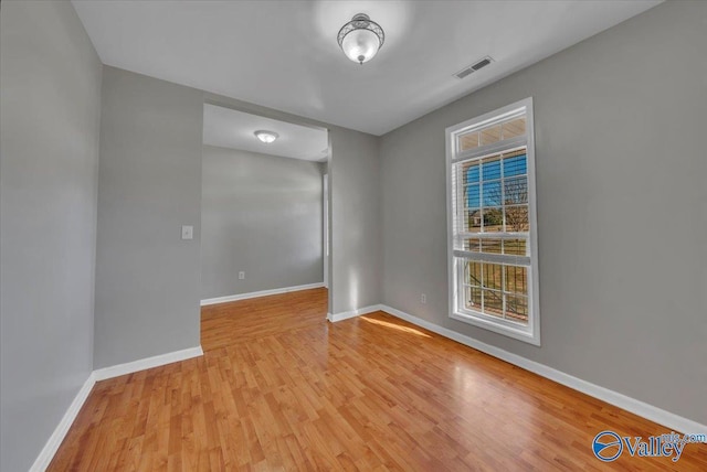 unfurnished room featuring wood finished floors, visible vents, and baseboards