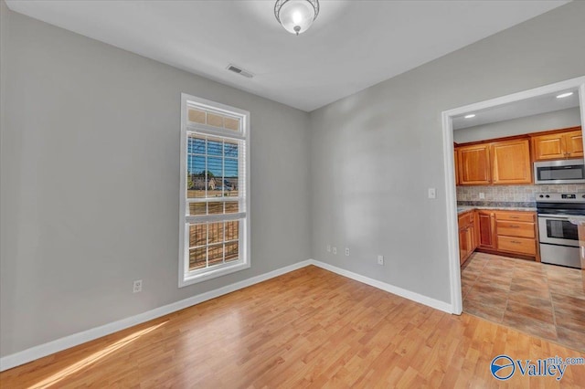 kitchen featuring baseboards, visible vents, appliances with stainless steel finishes, light wood-type flooring, and backsplash