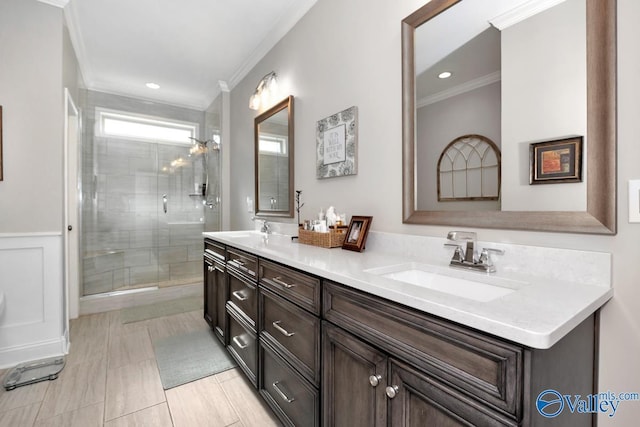 bathroom with crown molding, a stall shower, a sink, and double vanity