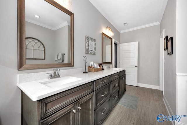 bathroom featuring crown molding, double vanity, visible vents, a sink, and baseboards