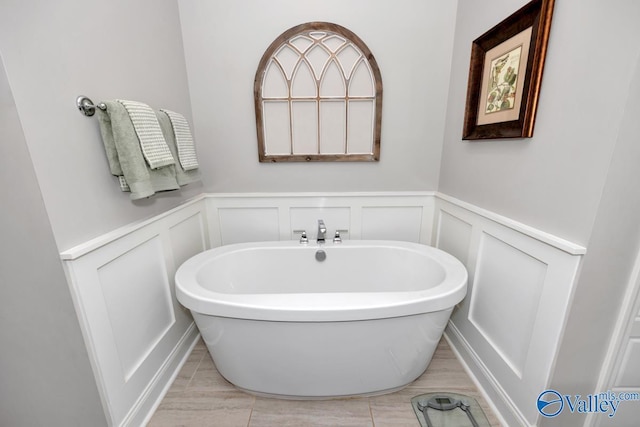 full bath featuring a freestanding tub, wainscoting, and a decorative wall