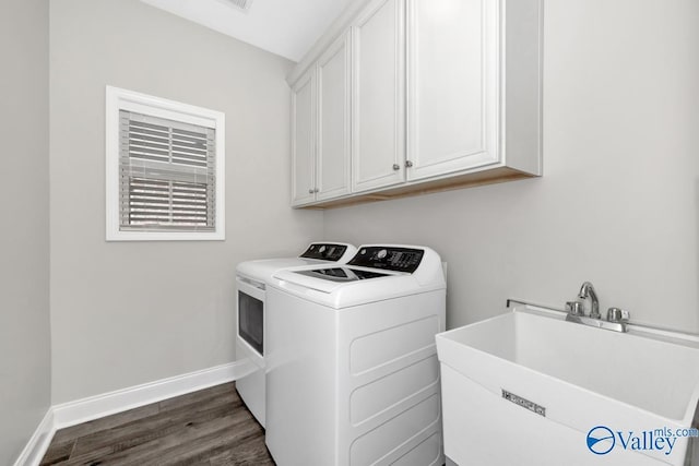 laundry area with cabinet space, baseboards, dark wood finished floors, washing machine and dryer, and a sink