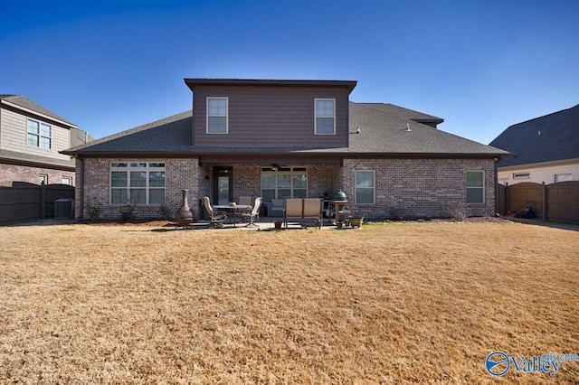 back of property with brick siding, fence, and a patio