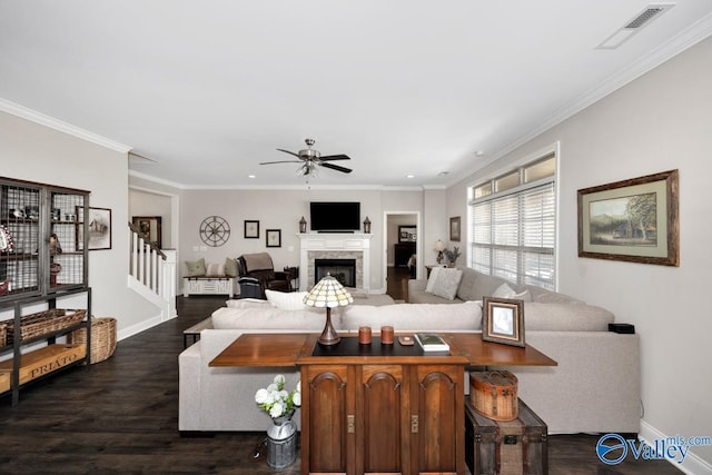 living room featuring baseboards, visible vents, dark wood-style flooring, crown molding, and a fireplace