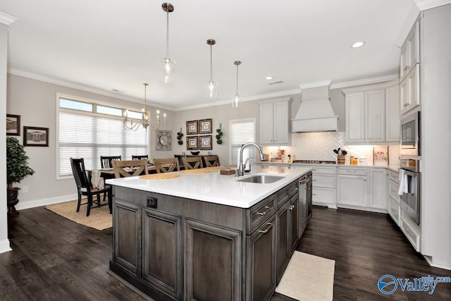 kitchen featuring crown molding, stainless steel appliances, light countertops, a sink, and premium range hood