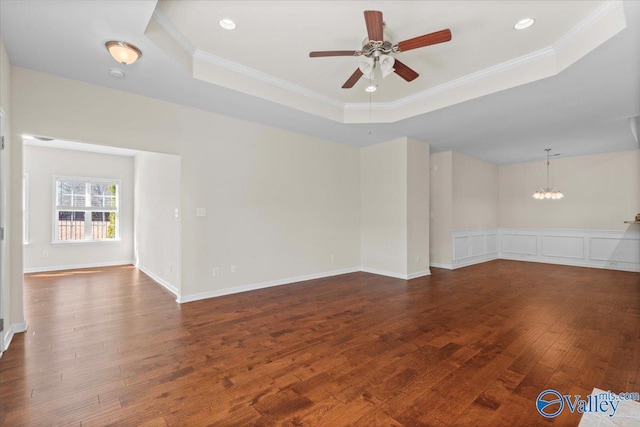 spare room with a tray ceiling, ceiling fan with notable chandelier, ornamental molding, and hardwood / wood-style flooring