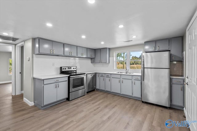 kitchen featuring light hardwood / wood-style flooring, gray cabinetry, and stainless steel appliances