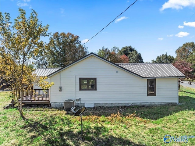 view of side of home with a wooden deck, a lawn, and central AC unit