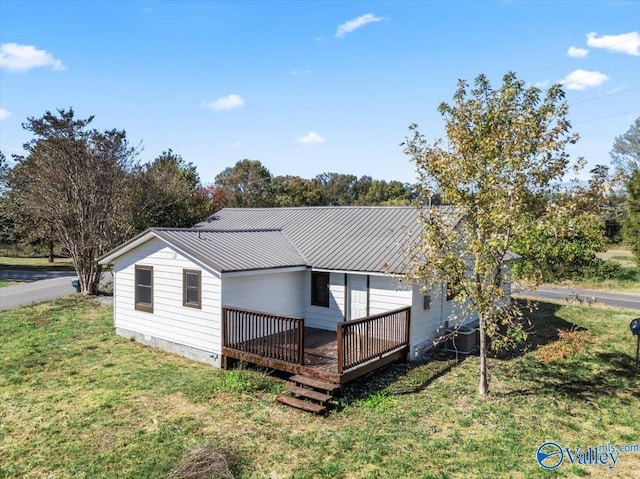 rear view of property featuring a wooden deck and a lawn