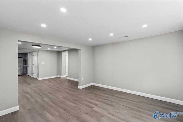 basement featuring wood-type flooring and stainless steel refrigerator