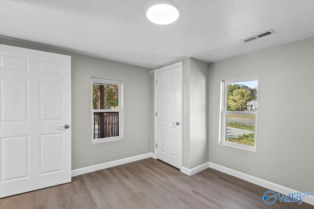 unfurnished bedroom featuring multiple windows and hardwood / wood-style flooring