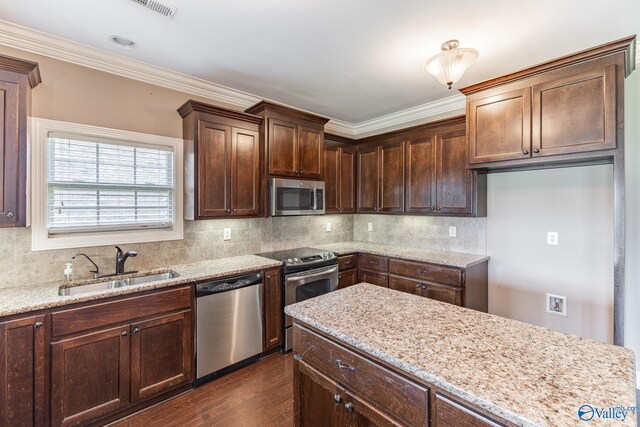 kitchen with decorative backsplash, appliances with stainless steel finishes, dark hardwood / wood-style floors, and light stone countertops