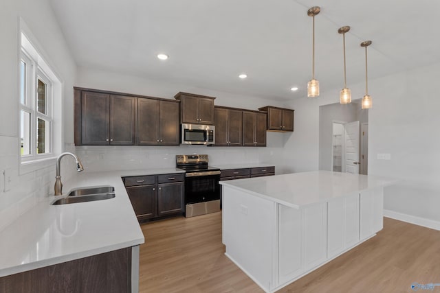 kitchen featuring sink, appliances with stainless steel finishes, gray cabinetry, hanging light fixtures, and a kitchen island