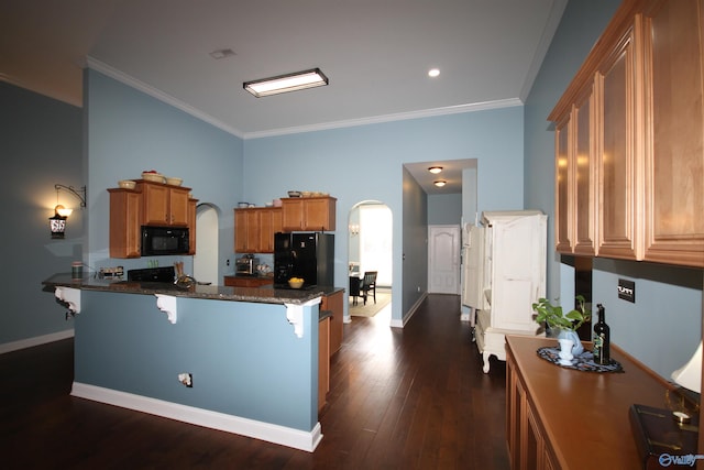 kitchen with dark wood-type flooring, black appliances, ornamental molding, a kitchen bar, and kitchen peninsula