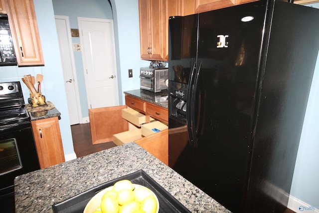 kitchen with dark stone countertops and black appliances